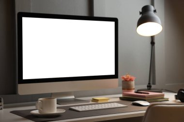 Ofisteki beyaz masa üzerinde beyaz ekran ve gri hasırlı bilgisayar. Şık bir iş yeri