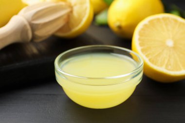 Taze limon suyu, meyveler ve sıkma siyah ahşap masa, yakın plan.