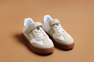 Kahverengi arka planda bir çift şık çocuk ayakkabısı, yakın plan.