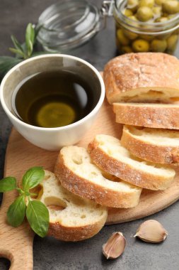 Ciabatta dilimleri, baharatlar ve zeytinler gri masada, yakın plan.