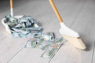 Süpürge ile dolar banknotları süpürme faraş üzerinde hafif ahşap zemin, seçici odak