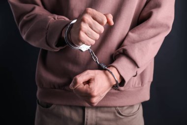 Siyah arka planda kelepçeli adam, yakın plan.