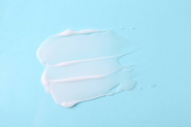 Açık mavi arka planda nemlendirici krem örneği, üst görünüm