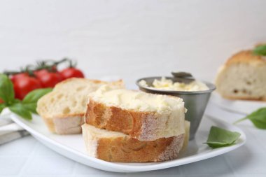 Beyaz fayanslı masada tereyağlı ve fesleğenli baget dilimleri, yakın plan. Metin için boşluk