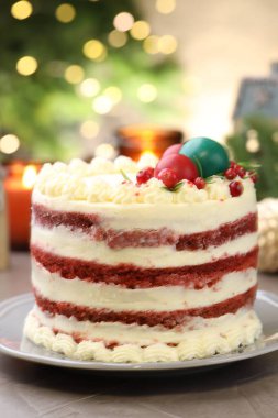 Noel dekorlu lezzetli sünger kek ve gri desenli masa üzümlü üzümlü, bulanık ışıklara karşı, yakın plan. Bokeh etkisi