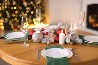 Güzel bir Noel sofrası, tabaklar, bardaklar ve yanan mumlarla dekoratif bir odada, yakın plan. Bokeh etkisi
