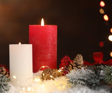 Masada yanan mumlar ve Noel dekoru. Arka planda bulanık ışıklar, yakın plan. Bokeh etkisi