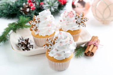 Noel dekorlu lezzetli kekler ve beyaz ahşap masa üzerinde tarçın, yakın plan.