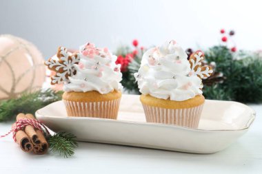 Noel dekorlu lezzetli kekler ve beyaz ahşap masa üzerinde tarçın, yakın plan.