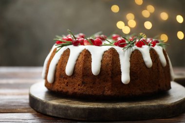 Üzerinde krema, kızılcık ve biberiye olan nefis bir Noel pastası. Gri arka planda, bulanık ışıklı, yakın plan. Bokeh etkisi