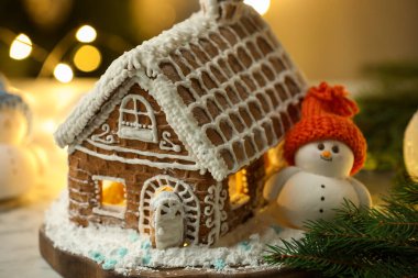 Kremalı, şekerli, pudra şekerli ve Noel dekorlu güzel zencefilli ev bulanık ışıklara karşı, yakın çekim