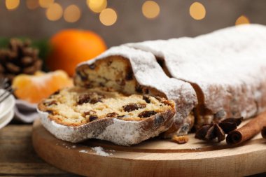 Geleneksel Noel Stollen, şeker, baharat, mandalina ve ahşap masa üzerindeki şenlikli dekor, yakın plan. Bokeh etkisi