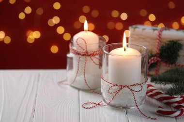 Noel fenerleri ve beyaz ahşap masa üzerindeki şenlikli dekor kırmızı arka planda bulanık ışıklar, yazı için yer. Bokeh etkisi