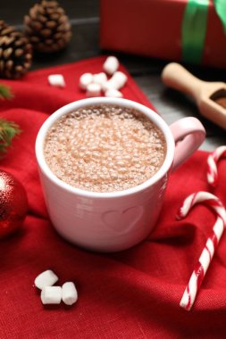 Lezzetli sıcak kakao bardakta, marşmelov ve Noel dekoru masada, yakın plan.