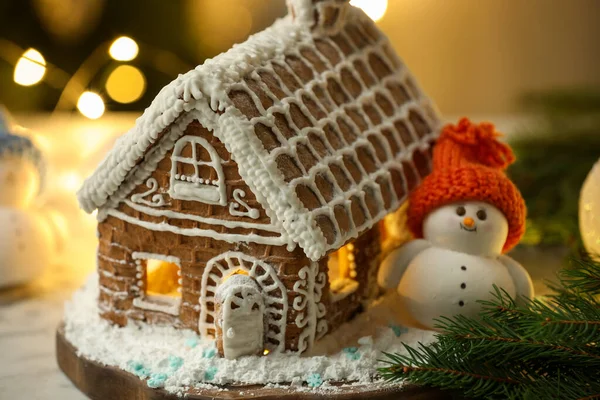 Kremalı, şekerli, pudra şekerli ve Noel dekorlu güzel zencefilli ev bulanık ışıklara karşı, yakın çekim