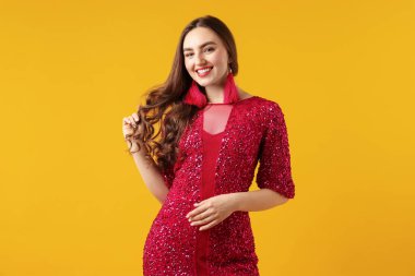 Turuncu arka planda güzel giyimli genç bir kadın.