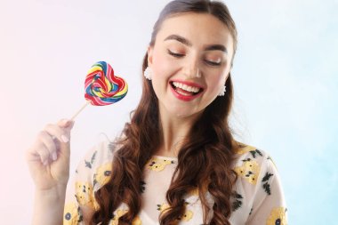 Açık mavi arkaplanda dumanlı lolipopu olan mutlu kadın.