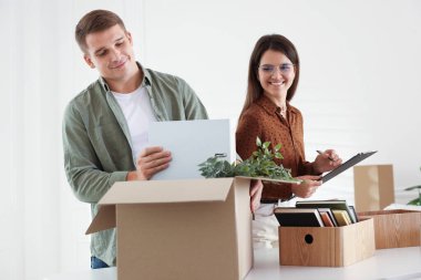 Taşınma günü. İşçiler ofisteki karton kutulara farklı eşyalar koyuyorlar.