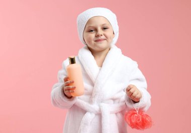 Pembe arka planda banyo lifi ve kozmetik ürünü olan hoş bir kız.