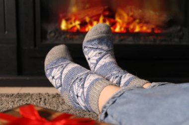 Sıcak çoraplı bir kadın şöminenin başında oturuyor, yakın plan. Noel sezonu