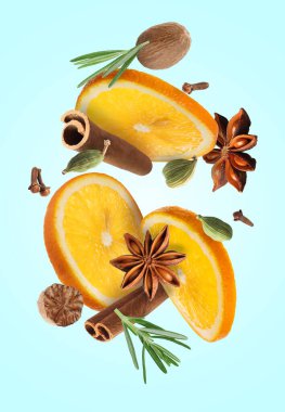 Sıcak şarap malzemeleri: açık mavi zemine düşen portakal dilimleri ve baharatlar. Geleneksel Noel içkisi