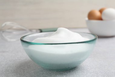 Gri desenli masada kasede yumurta beyazı çırpmak. Yakın plan.