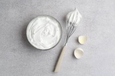 Yumurta beyazlarını kasede çırpmak, yumurta kabuğu ve çırpmak gri desenli masa, düz uzanmak
