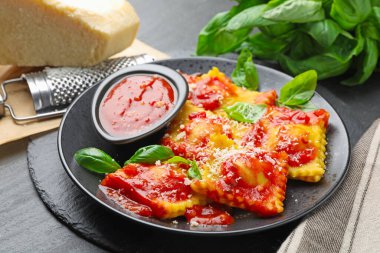 Gri masada domates soslu, peynirli, rendelenmiş ve fesleğenli lezzetli ravioli.