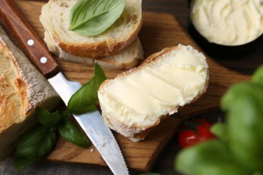 Tahta masada tereyağlı, fesleğenli, domatesli ve bıçaklı baget dilimleri.