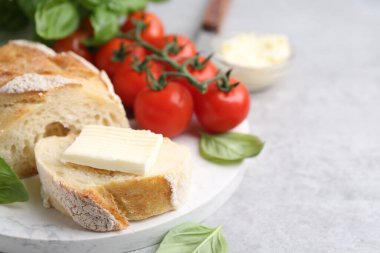 Açık gri masada tereyağlı, fesleğenli ve domatesli baget dilimleri, yakın plan. Metin için boşluk