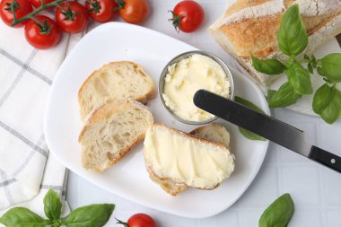 Tereyağlı, fesleğenli, domatesli ekmek dilimleri ve beyaz fayanslı bir bıçak.