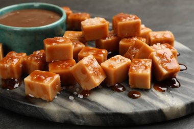 Koyu dokulu masada tuz ve karamel soslu lezzetli şekerler, yakın plan.