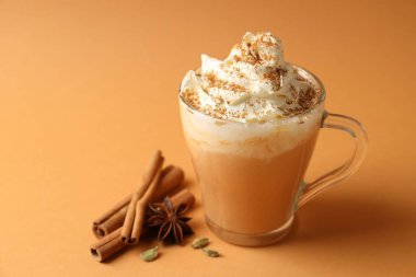 Turuncu arka planda kremalı ve baharatlı balkabaklı latte, yakın plan. Metin için boşluk