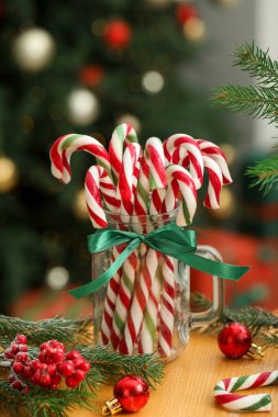 Duvarcı kavanozunda bir sürü şeker kamışı ve ahşap masada bulanık ışıklara karşı Noel dekoru. Bokeh etkisi