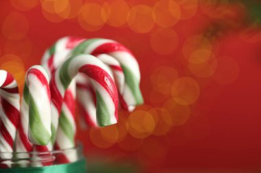 Kırmızı arkaplanda şeker kamışları, bulanık ışıklar, yakın çekim ve metin için boşluk. Noel hediyesi