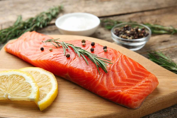 Bir parça somon fileto, baharat ve limon ahşap masada, yakın plan.