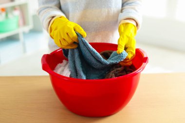 Kadın havluları plastik havluyla yıkıyor, ahşap masada, yakın plan.