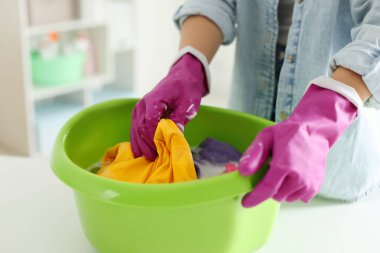 Beyaz masada plastik leğende çamaşır yıkayan bir kadın, yakın plan.