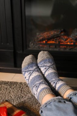 Evde şöminenin yanında sıcak çorap giyen bir kadın, yakın çekim. Sıcak kış akşamı