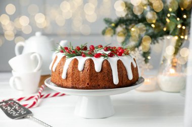 Beyaz ahşap masada kremalı, kızılcıklı ve biberiyeli lezzetli bir Noel pastası.
