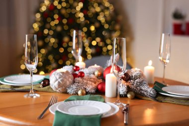 Güzel bir Noel sofrası, tabaklar, bardaklar ve yanan mumlarla dekoratif bir odada, yakın plan. Bokeh etkisi