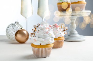 Noel dekorlu lezzetli kekler ve beyaz masada şampanya, yakın plan. Bokeh etkisi