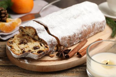 Geleneksel Noel Stollen, şeker, baharat, mandalina ve ahşap masa üzerindeki şenlikli dekor ile yakın plan