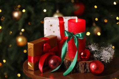 İçerideki Noel ağacının yanındaki masada yanan mum ve şenlikli dekor, yakın plan.