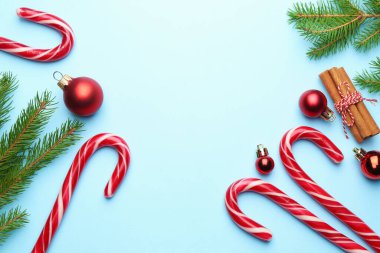 Lezzetli şeker kamışları, tarçın çubukları, köknar dalları ve açık mavi arka planda mücevherler, metin için yeri olan düz bir yer. Mutlu Noeller ve mutlu yıllar.