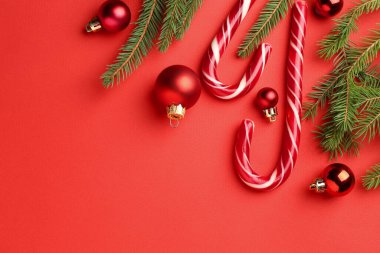 Lezzetli şeker kamışları, köknar ağacı dalları ve kırmızı arka planda mücevherler, yazı için yeri olan düz bir yer. Mutlu Noeller ve mutlu yıllar.