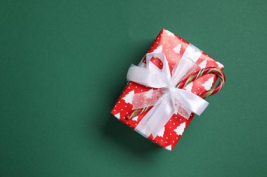 Yeşil arka planda baston şekerle süslenmiş Noel hediyesi, üst manzara. Metin için boşluk