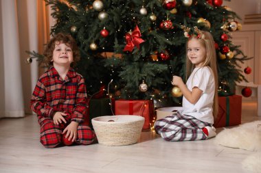 Pijamalı çocuklar evde Noel ağacı süslüyorlar.