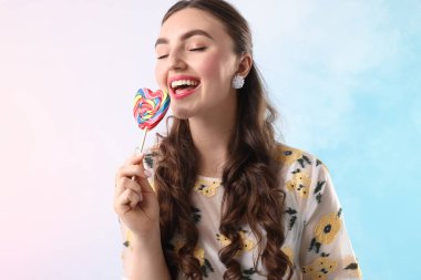 Açık mavi arkaplanda dumanlı lolipopu olan mutlu kadın.