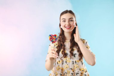 Açık mavi arka planda lolipopu olan mutlu kadın dumanlı, mesaj için yeri var.